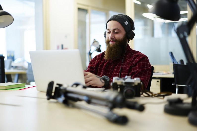 A man listening to music on headphones types at a laptop