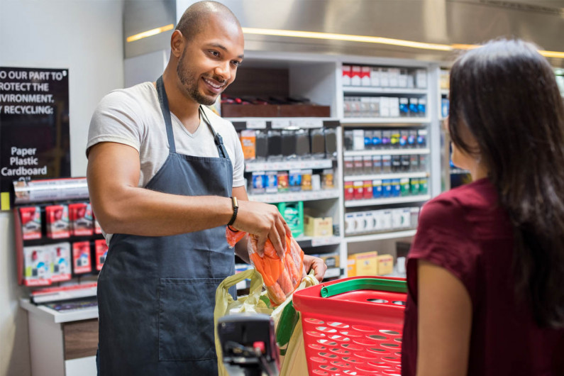 A checkout operator packs groceries in a supermarket