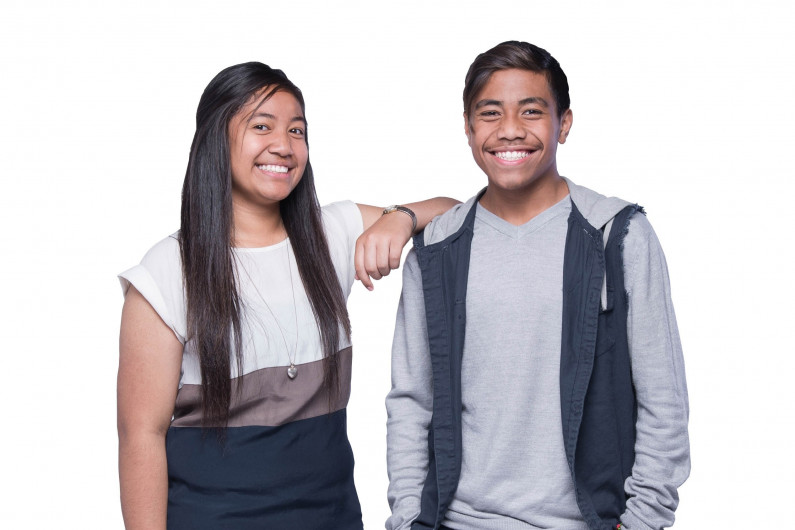 Two young people stand next to each other smiling