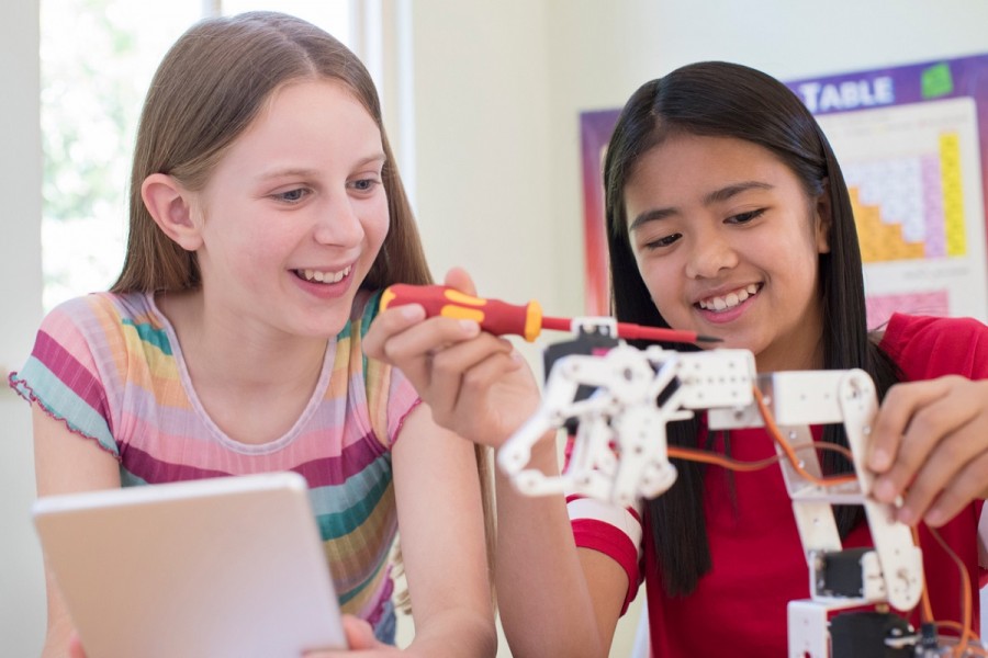 Two teenage girls building a robot 