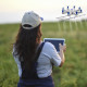 a woman standing in a field operates a drone