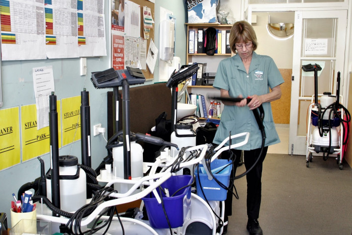 Julie Pope checks the attachment to a steam cleaner in a hospital office. Other steam cleaners are also pictured
