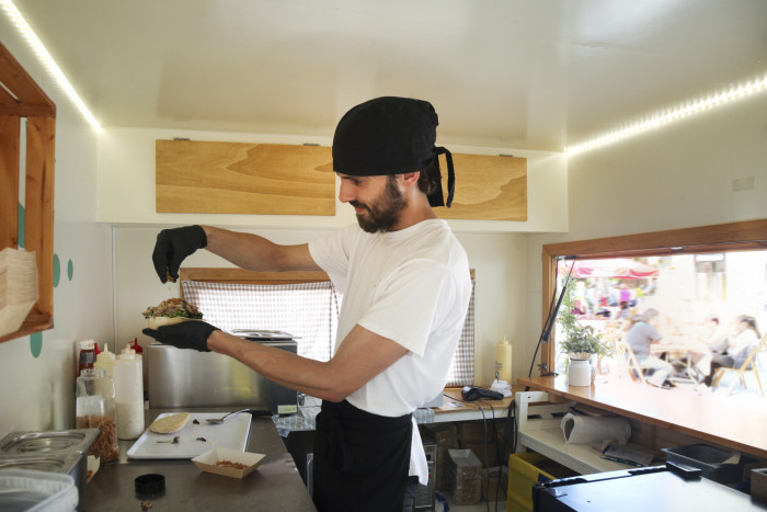 A cook prepares a burger in a food truck