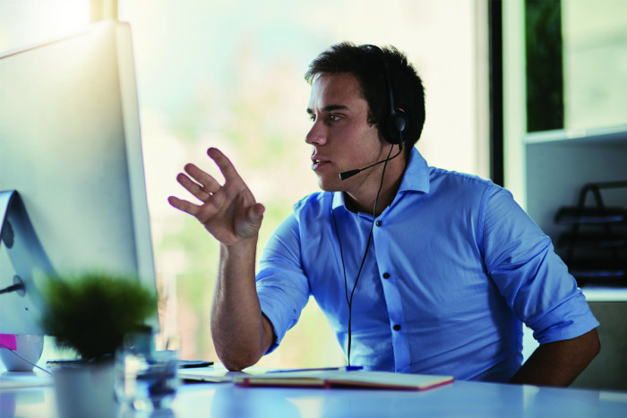 A male debt collector in a call centre talks to a customer on the phone