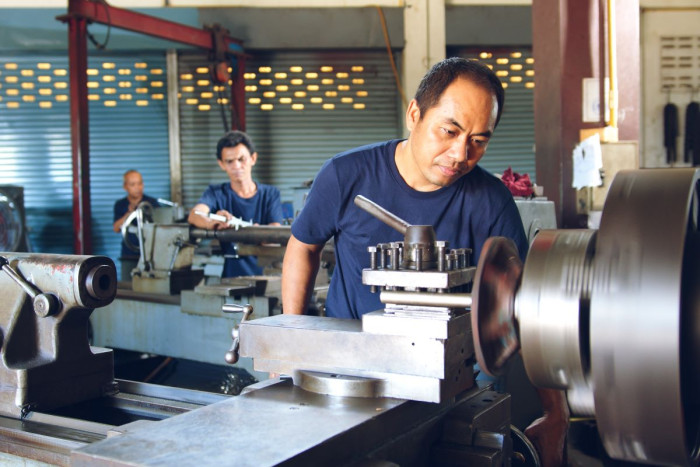 A man uses a metal lathe in a workshop 