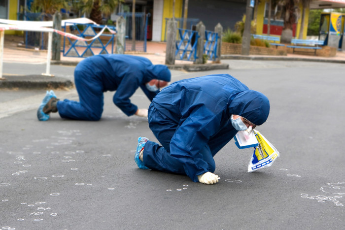 Two scientists kneeling and searching for evidence on the ground 