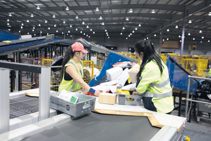 Two mail and parcel sorters processing parcels at a mail centre