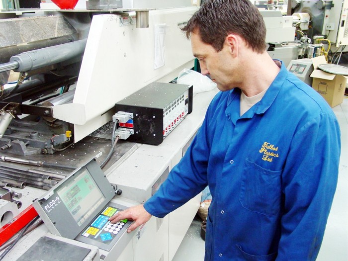 Andrew McLeod presses a button on the plastics machine to test that it is working