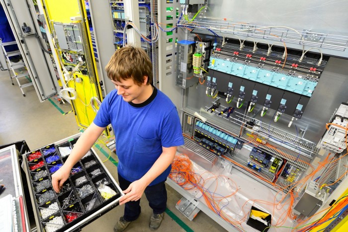 A product assembler gets parts from a drawer to put into a machine he is building