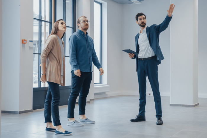 A property manager shows two clients an empty office space