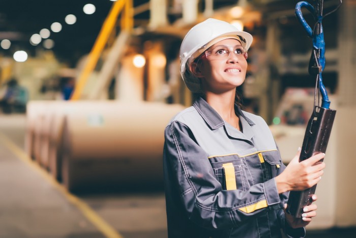 A female paper mill operator pushes buttons on a crane