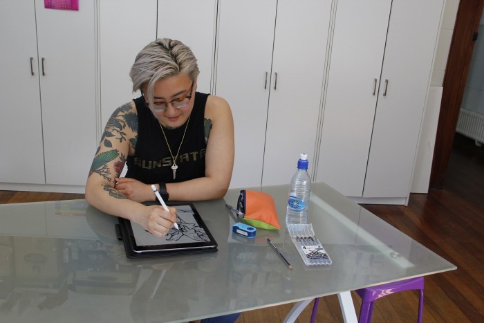 Rose Hu at a table drawing a draft tattoo on an iPad 