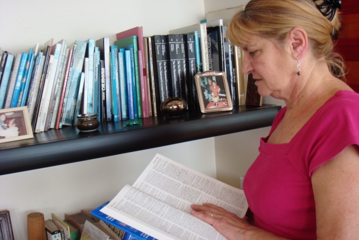 Chantal Taylor-Bizet checking a dictionary as she stands by a bookshelf