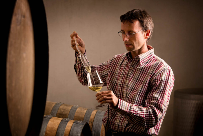 A winemaker sampling wine from a barrel