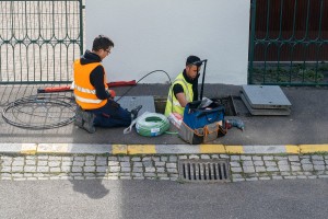 One man is in a manhole and another man is feeding him fibre-optic cable.