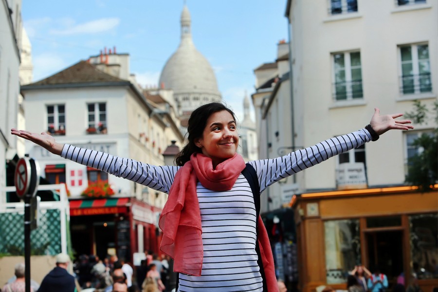 A girl stands in Montmartre, Paris with her arms outstretched